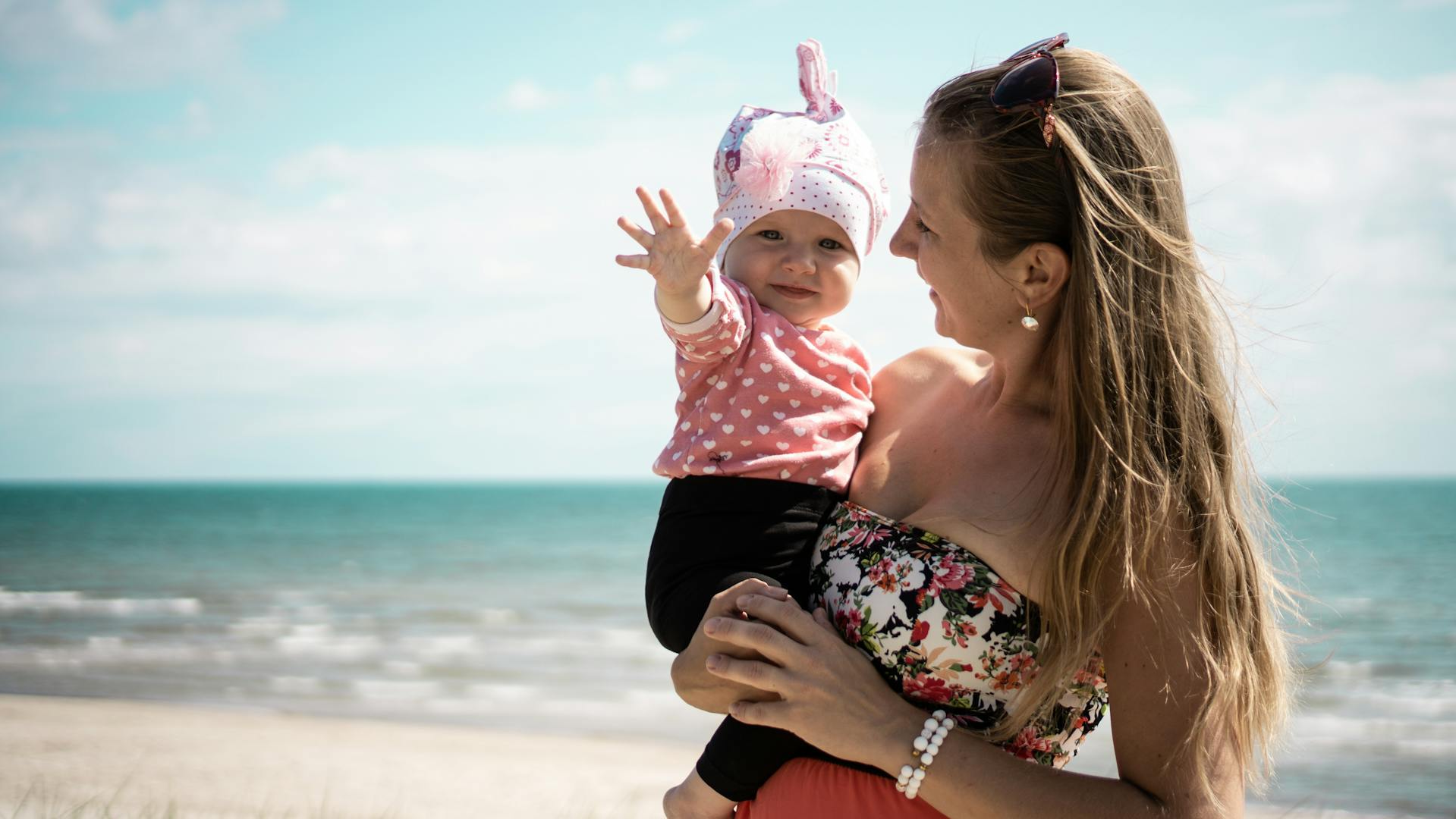 Maman souriante portant son bébé en extérieur symbole de sorties de sereines - Chouchous les bébés