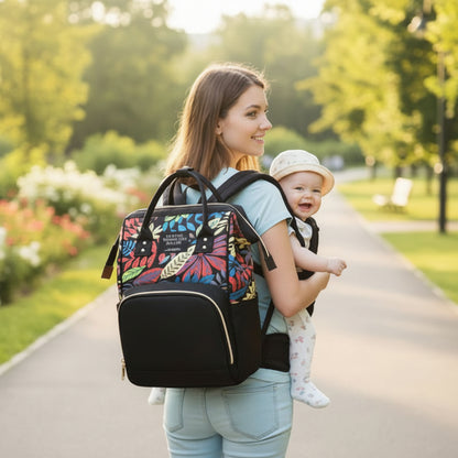 Sac à dos à langer L'Héritage™ ergonomique — maman et bébé en porte-bébé sur un sentier ensoleillé